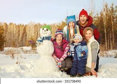 Portrait Of A Cheerful Family With Snowman. Happy Children And Parents In The Winter Outdoors