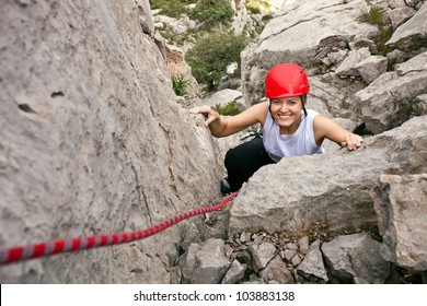 Portrait Of Cheerful Female Climber Ascending A Rock
