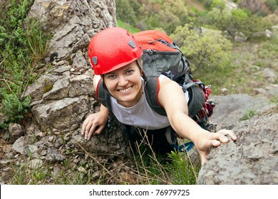 Portrait Of Cheerful Female Climber Ascending A Rock