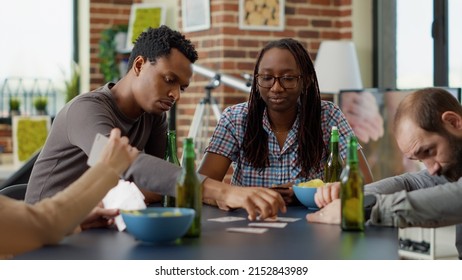 Portrait Of Cheerful Female Person Playing Board Games With Friends, Having Fun With Cards Strategy And Competition. Young People Enjoying Gameplay On Table, Having Beer And Snacks.