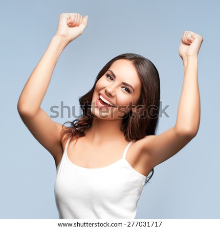 Portrait of cheerful gesturing smiling young woman, over grey background