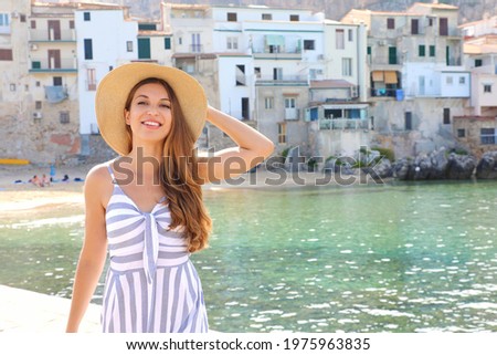 Portrait of cheerful girl in seaside town overlooking sea looking at camera