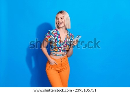Portrait of cheerful gorgeous person hold smart phone look empty space ad isolated on blue color background