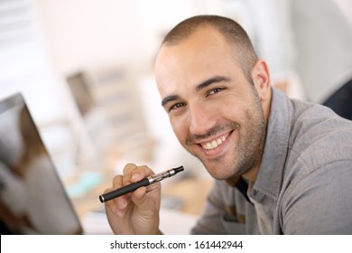 Portrait of cheerful guy smoking with e-cigarette