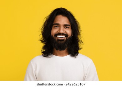 Portrait of cheerful handsome long-haired bearded young indian man in white posing isolated on yellow bright studio background, smiling at camera. Millennials lifestyle concept - Powered by Shutterstock