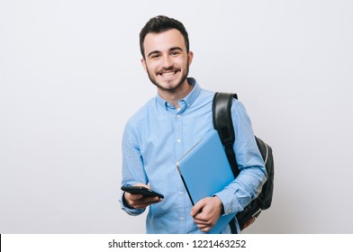 Portrait of cheerful handsome man holding laptop and phone over white background and looking at the camera. - Powered by Shutterstock