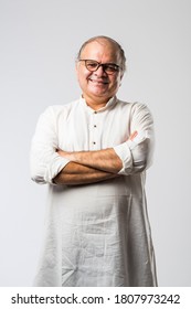 Portrait of cheerful Indian retired old man wears white kurta, pointing or presenting or in hands folded pose - Shutterstock ID 1807973242