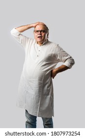 Portrait of cheerful Indian retired old man wears white kurta, pointing or presenting or in hands folded pose - Shutterstock ID 1807973254