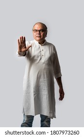 Portrait of cheerful Indian retired old man wears white kurta, pointing or presenting or in hands folded pose - Shutterstock ID 1807973260