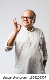 Portrait of cheerful Indian retired old man wears white kurta, pointing or presenting or in hands folded pose - Shutterstock ID 1808206309