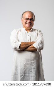 Portrait of cheerful Indian retired old man wears white kurta, pointing or presenting or in hands folded pose