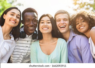 Portrait of cheerful interracial teen friends posing at camera outdoors, smiling and laughing, enjoying spending time together, closeup - Powered by Shutterstock