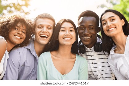 Portrait of cheerful interracial teen friends posing at camera outdoors, smiling and laughing, enjoying spending time together, closeup - Powered by Shutterstock