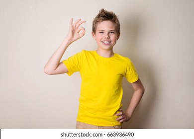 Portrait of a cheerful kid in braces showing okay gesture. Health, education and people concept.