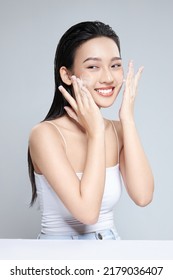 Portrait of cheerful laughing Asian woman applying foam for washing on her face with attractive appearance. Skincare spa relax concept. Isolated on grey background - Shutterstock ID 2179036407