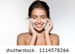 Portrait of cheerful laughing woman applying foam for washing on her face. Lovely brunette with attractive appearance. Skincare spa relax concept. Isolated on grey background