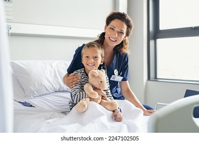 Portrait of cheerful little boy holding teddy bear while sitting with nurse on gurney at hospital. Young paediatrician doctor visiting and comforting hospitalised child at private clinic. - Powered by Shutterstock