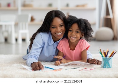 Portrait of cheerful loving african american mom and little girl with bushy hair daughter coloring together, laying on carpet at kids room, painting, embracing and smiling at camera, copy space - Powered by Shutterstock