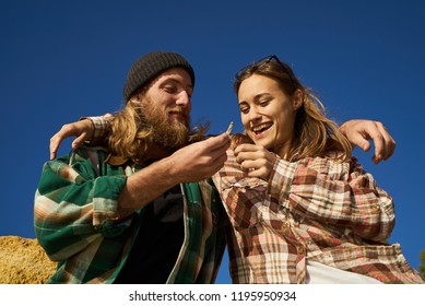 Portrait of cheerful male and female friends smoking a joint in blue sky background