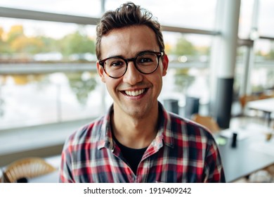 Portrait of a cheerful male professional in office. Businessman in casuals wearing eyeglasses looking at camera and smiling.