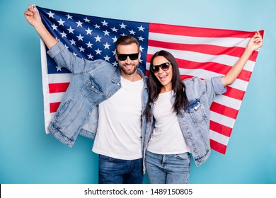 Portrait of cheerful married people in eyewear eyeglasses holding us flag screaming wearing  denim jeans jacket isolated over blue background - Powered by Shutterstock