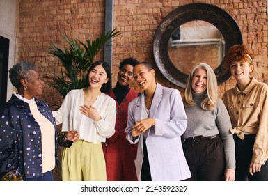 Portrait Of Cheerful Multiethnic Businesswomen Laughing And Smiling In Office With Exposed Brick Wall Interior