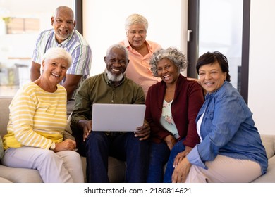 Portrait Of Cheerful Multiracial Senior Friends With Laptop Relaxing On Sofa At Nursing Home. Wireless Technology, Happy, Unaltered, Friendship, Togetherness, Support, Assisted Living, Retirement.