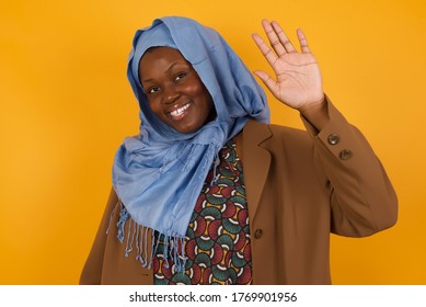 Portrait Of Cheerful, Outgoing Friendly-looking Young Woman Wearing Casual Clothes Raise One Hand And Wave, Saying Hi Or Hello And Smiling With Carefree Expression As Make Goodbye Or Welcome Gesture.