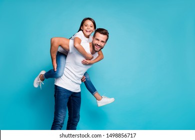 Portrait of cheerful people laughing piggyback wearing white t-shirt denim jeans isolated over blue background - Powered by Shutterstock