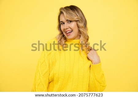 Portrait of cheerful playful young woman with blond hair showing tongue on yellow background. cute caucasian lady look at camera charmingly, dating concept, flirting, studio shot