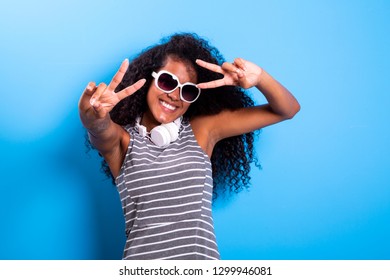 Portrait of cheerful positive woman having headphones dancing isolated on blue background 