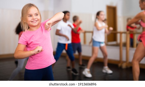 Portrait Of Cheerful Preteen Girl Practicing Dance Movements With Group Of Children In Choreography Class