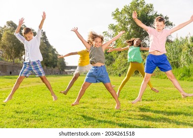 Portrait of cheerful preteen girls and boys jumping together in summer city park. Concept of happy childhood.. - Shutterstock ID 2034261518