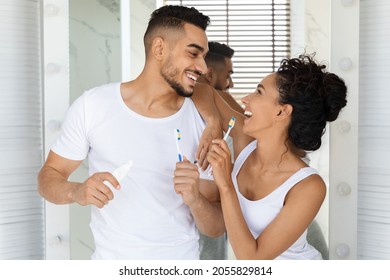 Portrait Of Cheerful Romantic Arab Couple Brushing Teeth And Having Fun In Bathroom Together, Young Middle Eastern Spouses Holding Toothbrushes And Smiling To Each Other, Enjoying Morning Routine - Powered by Shutterstock