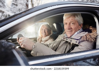 Portrait of cheerful senior couple driving car in winter, focus on senior man behind wheel looking at camera, copy space - Powered by Shutterstock