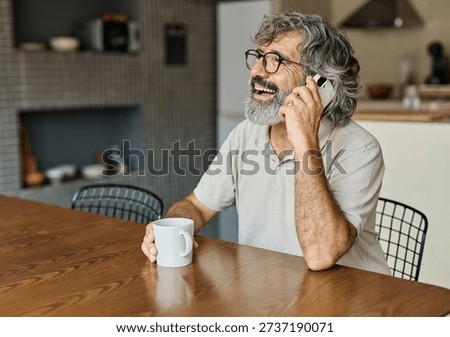 Portrait of a cheerful senior elderly man talking on phone at home