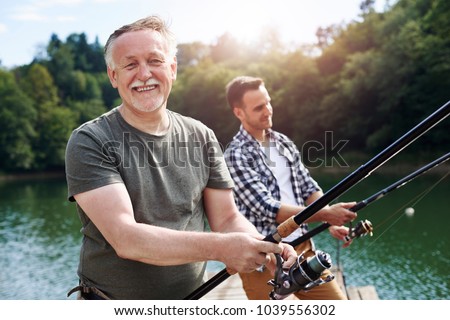Portrait of cheerful senior man fishing 
