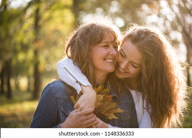 Retrato de alegre mulher sênior segurando folhas de outono com filha
