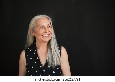 Portrait Of Cheerful Senior Woman With Long Grey Hair Over Black Background.