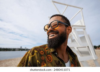 Portrait of cheerful and stylish african american man in sunglasses on beach - Powered by Shutterstock