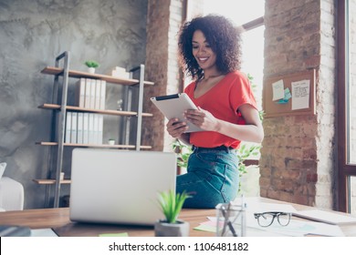 Portrait of cheerful stylish journalist in casual outfit sitting on desk holding gadget in hands using wi-fi internet in modern office with interior. Electronic wireless device concept - Powered by Shutterstock