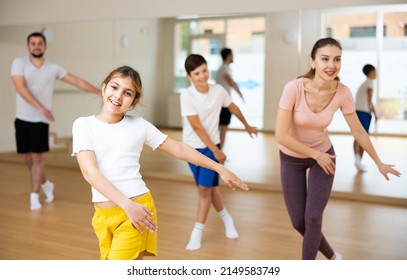 Portrait Of Cheerful Teen Girl Practicing Vigorous Movements In Dance Class With Brother And Parents. Family Active Lifestyle Concept