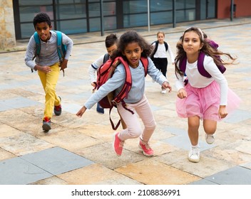 Portrait Of Cheerful Tween Boys And Girls With School Backpacks Running In Schoolyard In Spring Day.