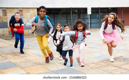 Portrait Of Cheerful Tween Boys And Girls With School Backpacks Running In Schoolyard In Spring Day.