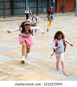 Portrait Of Cheerful Tween Boys And Girls With School Backpacks Running In Schoolyard In Spring Day.