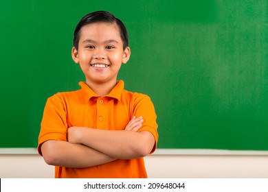 Portrait of cheerful Vietnamese schoolboy with his arms crossed
