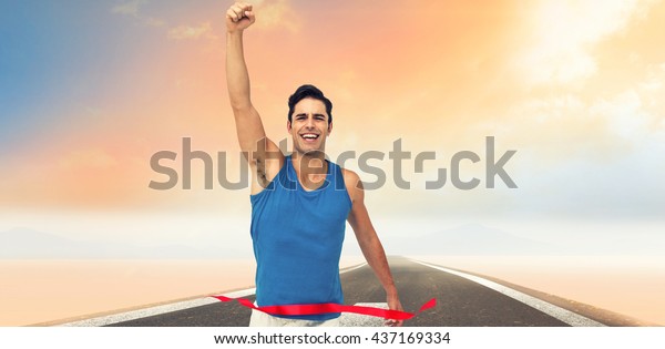 Portrait of cheerful winner athlete crossing\
finish line against road\
landscape