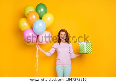 Portrait of cheerful woman hold helium baloons green dotted gift box she prepare for friends anniversary wear casual style pullover isolated over shine color background