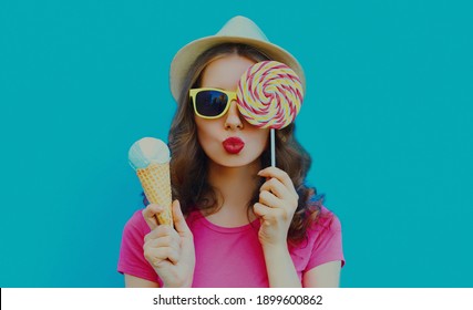 Portrait of cheerful woman with ice cream and lollipop on a blue background