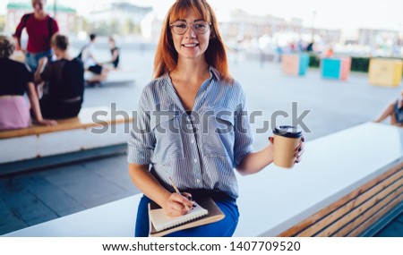 Portrait of cheerful woman in spectacles for vision correction enjoying time for learning and preparing for university exam, happy female student with caffeine beverage in hand smiling at camera